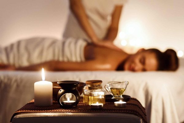 Aroma spa. Woman enjoying massage in luxury spa with candle on foreground